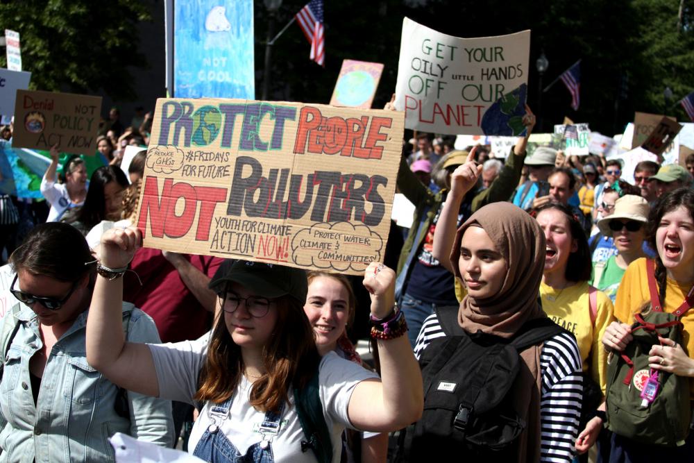 Women in foreground marching at rally and holding signs during Global Climate Strike in 2019 in Washington, DC 