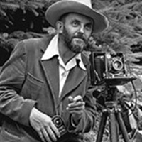 black and white image of a man and an old camera