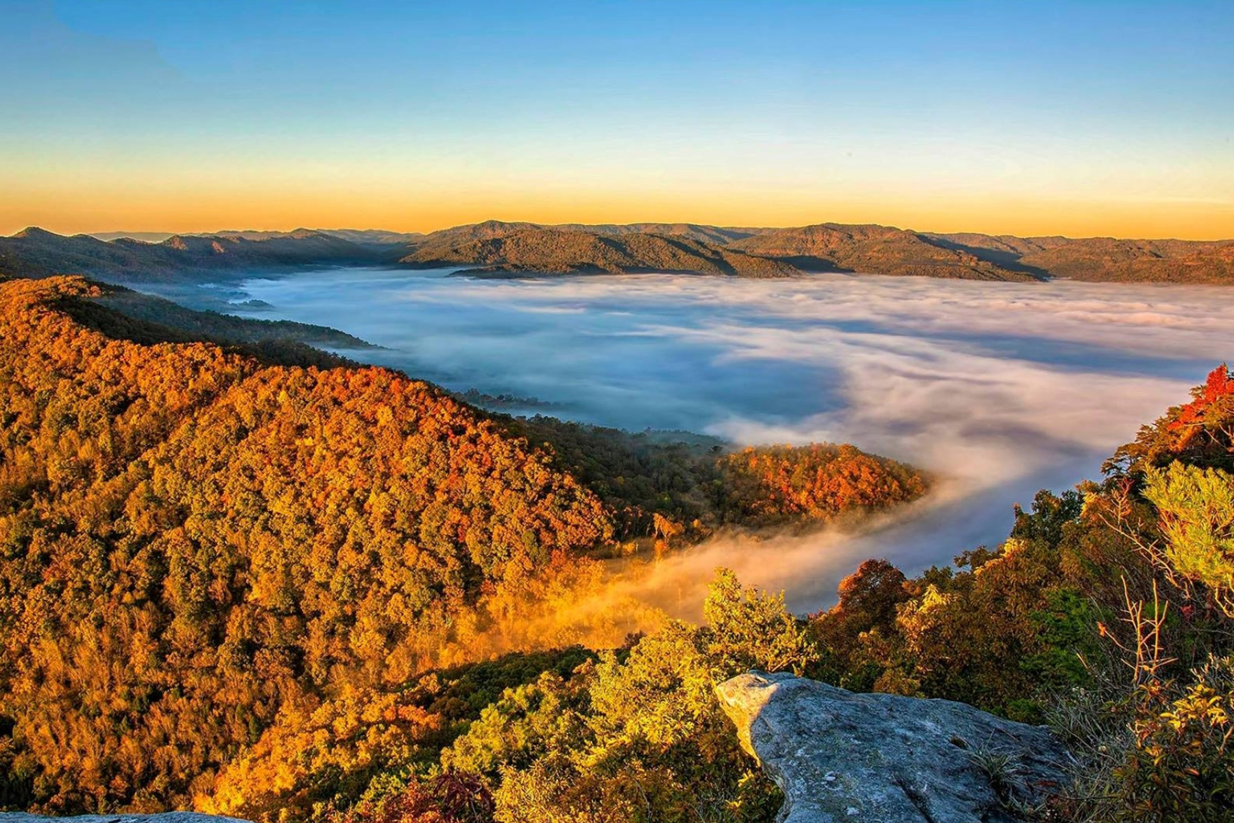 View of clouds on top of mountains with fall foliage