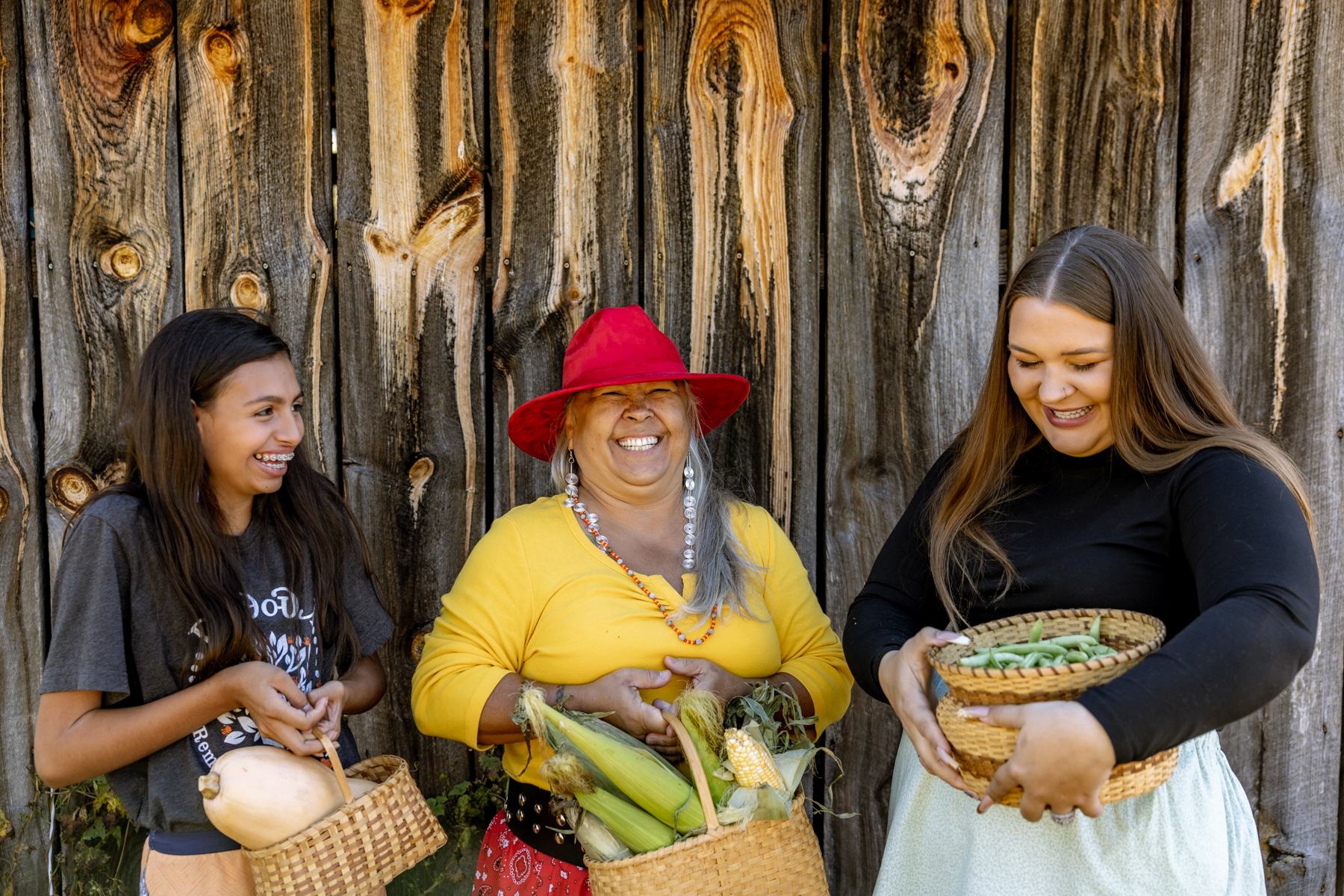 Ga-tli-so-di (Gather) the harvest of V-le-ni-do-hv (life) and a-ye-tsa-s-di (laughter), when we take care of the land, the land provides, we can take care of each other. Jasmine with squash, Nikki with corn and Faith with beans.