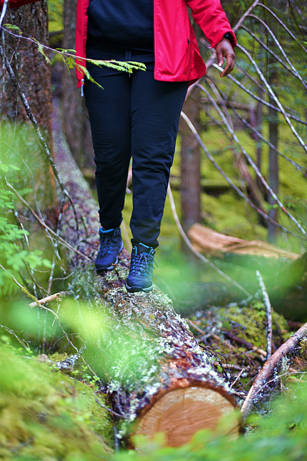 A woman walking across a log in the forest