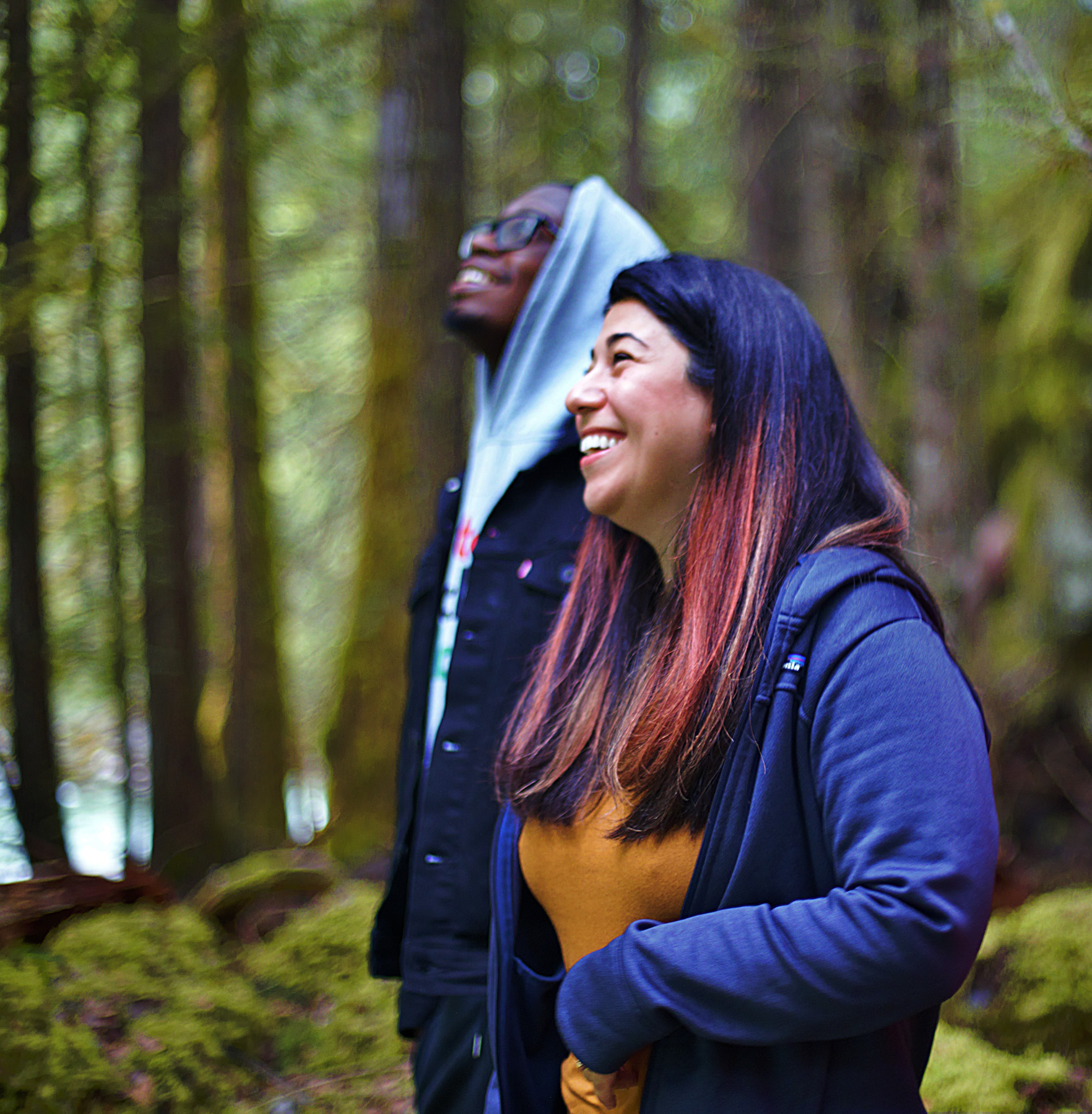 Two people laughing in the forest.