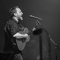 black and white picture of man singing while playing the guitar