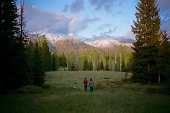 Two people in a meadow gazing at snow-capped peaks. Copyright The Wilderness Society