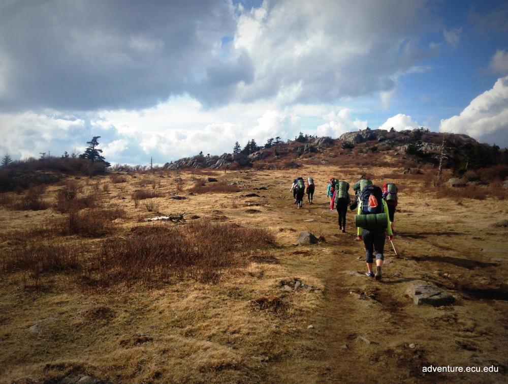students hiking through valley with backpacking gear