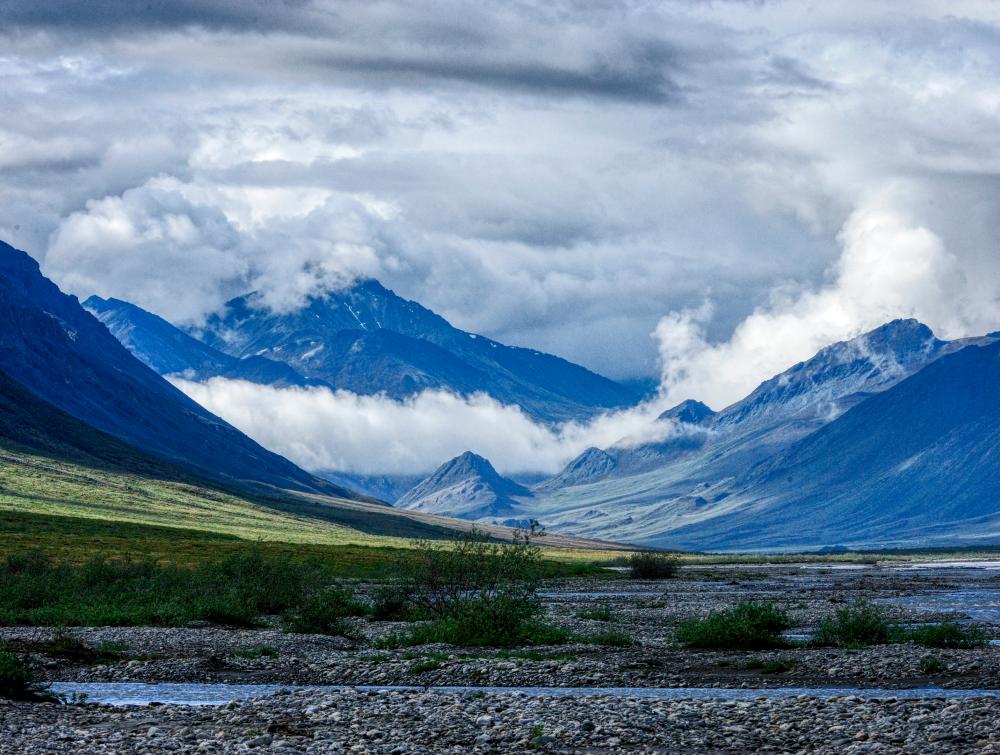 Sun and clouds mix on a summer day along the Hulahula River valley as it flows north from Alaska's Brooks Range mountains to the Coastal Plain in the Arctic National Wildlife Refuge.