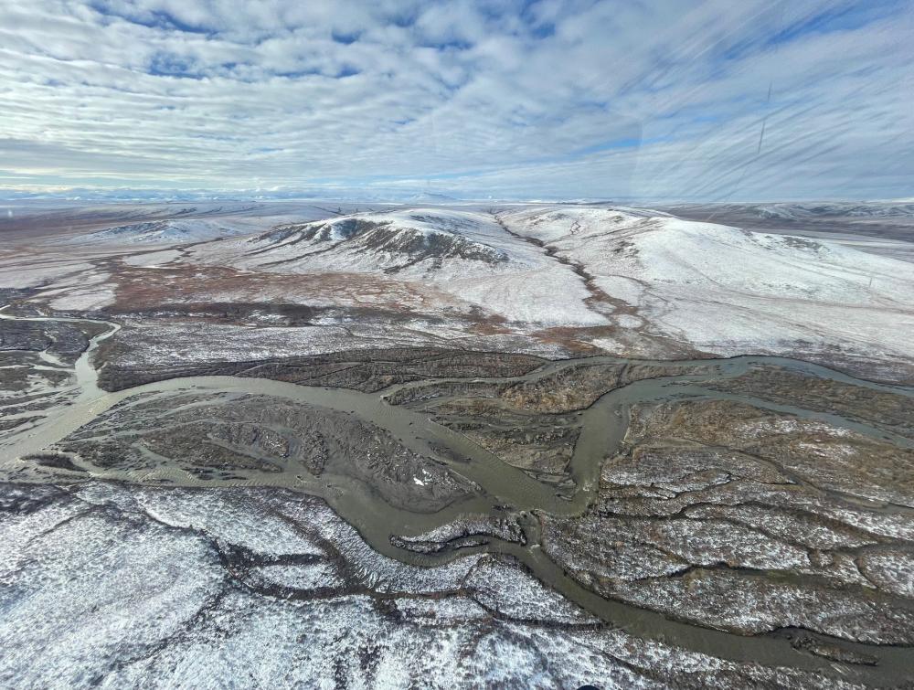 Aerial view of river with snow-fringed mountains in the background