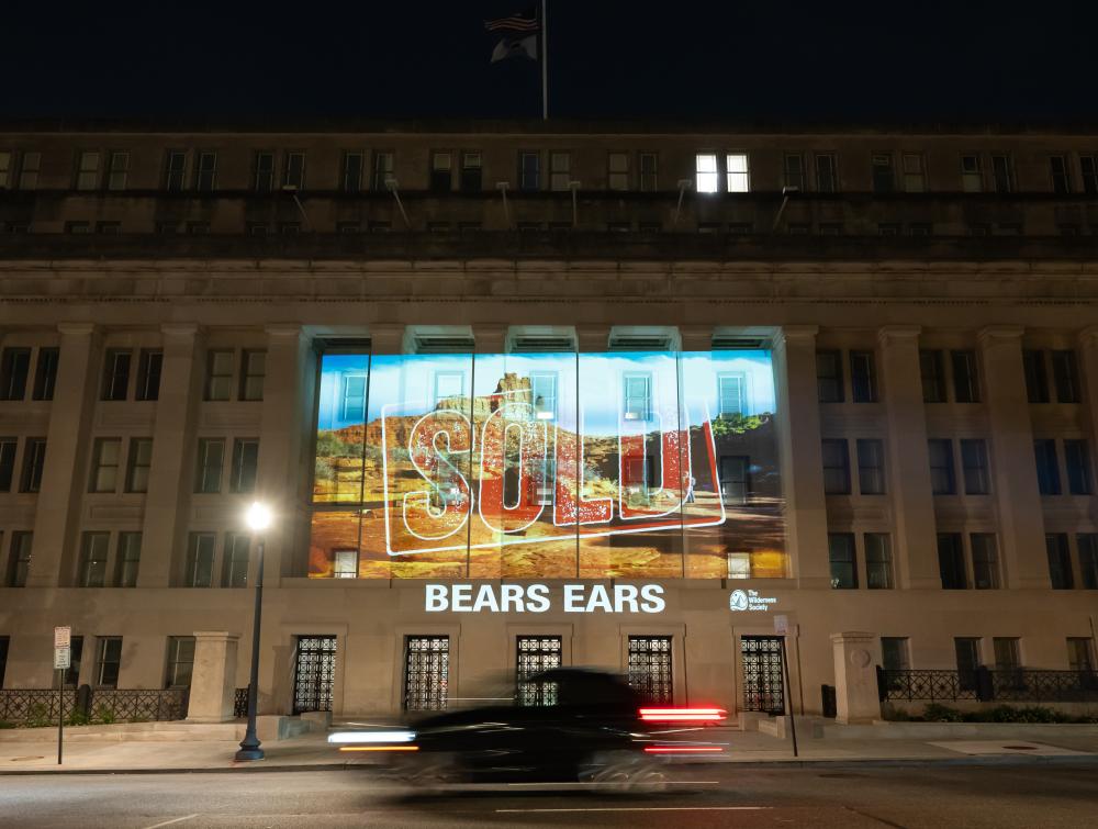 A "SOLD" message projected onto the Department of Interior headquarters