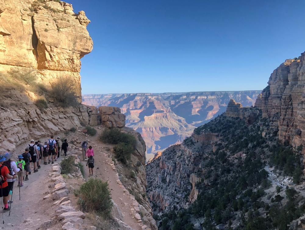 Procession of hikers on a trail near the Grand Canyon