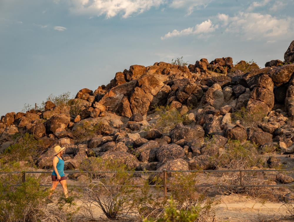 Woman hiking in front of boulders with petroglyphs.