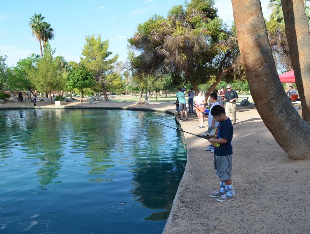Boy fishing off a cement dock at South Mountain Park in Phoenix, Arizona
