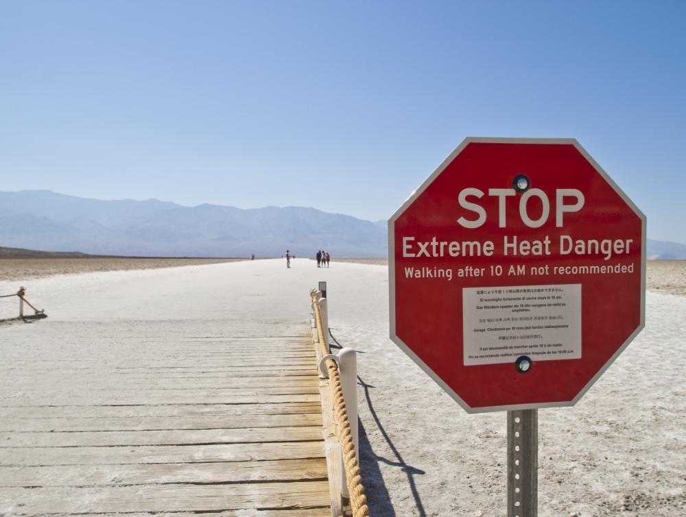 stop sign in the desert that says "extreme heat caution" 