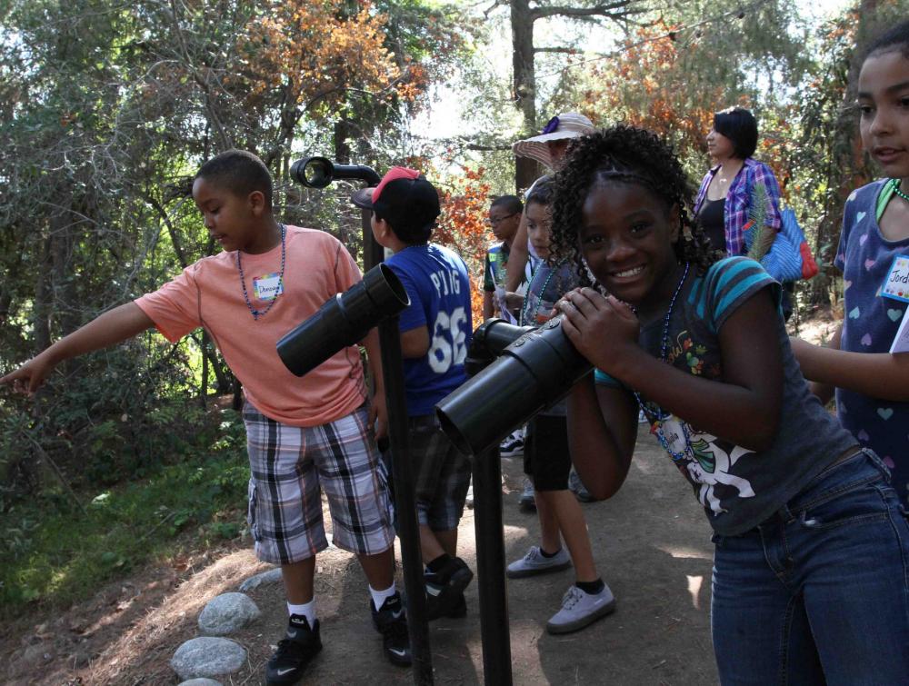 Girl looks through mounted telescope in a group of kids at an "Every Kid in a Park" event in Los Angeles County, California, in 2015