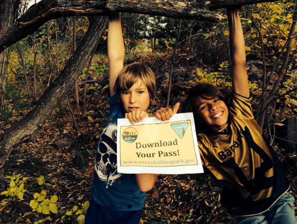 Two kids hold a sign reading "Download Your Pass" at an Every Kid in a Park event in 2015, Lakewood, Colorado