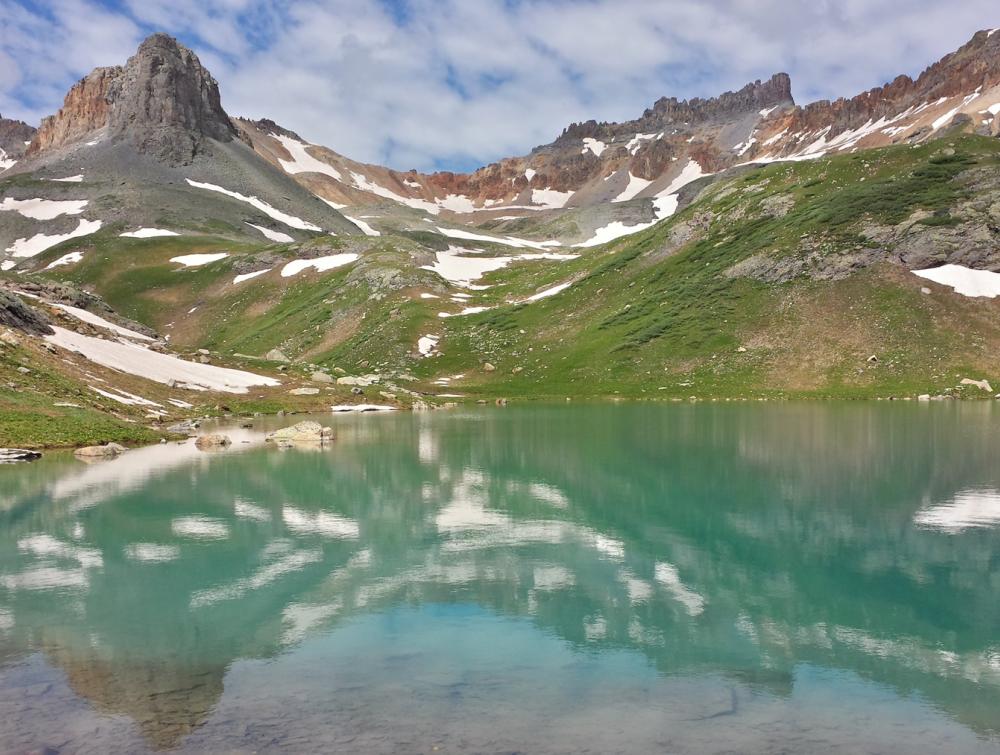 Brilliant blue lake surrounded by snow-streaked mountainous terrain