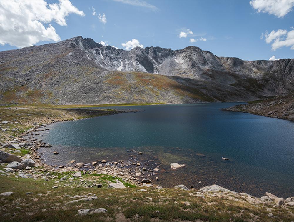 A beautiful lake on a blue sky day, a mountain is in the background