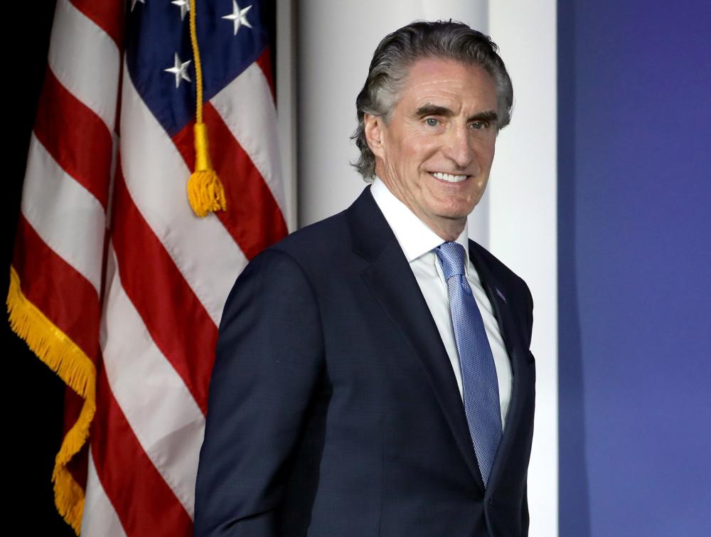 Man in suit standing in front of American flag