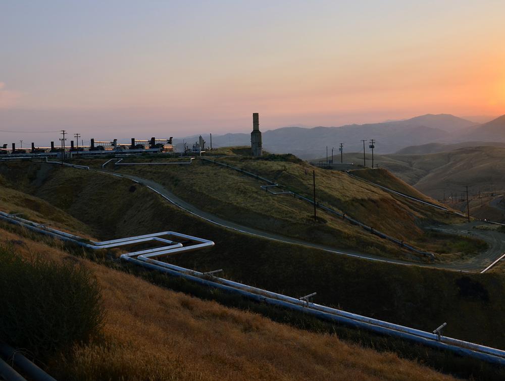 Instalaciones de petróleo y gas en una colina mientras se pone el sol.