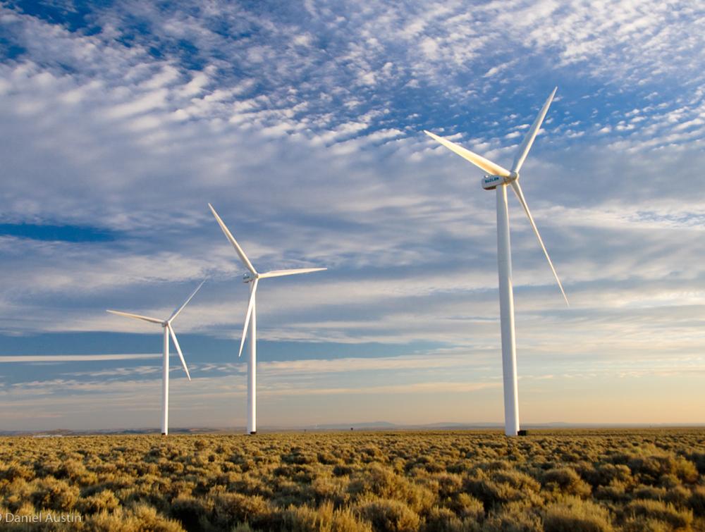 Three wind turbines against a blue sky with sparse clouds.