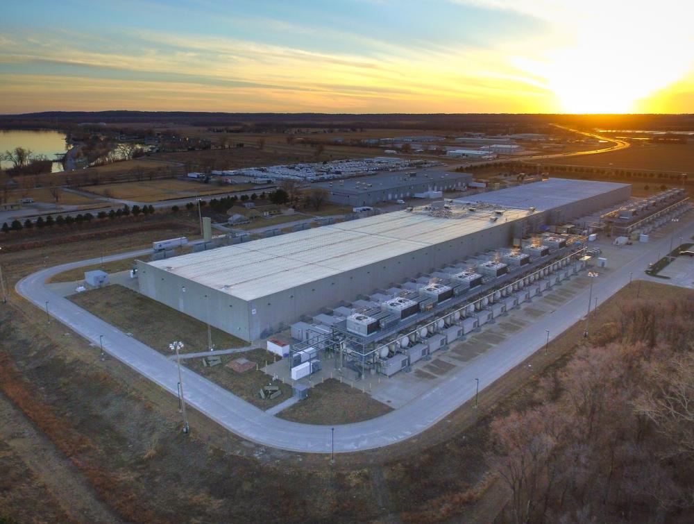 Warehouse-like building near body of water with sun shining on the horizon