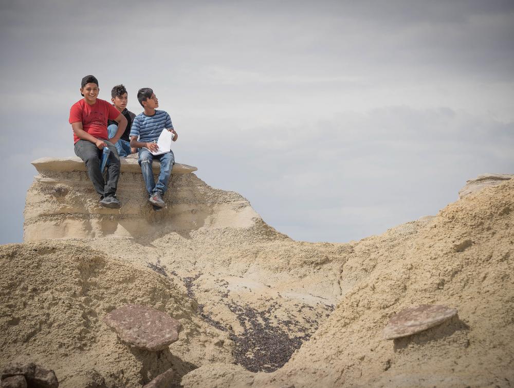 Three teenagers sit on a rock formation at Ah-Shi-Sle-Pah Wilderness Study Area, New Mexico