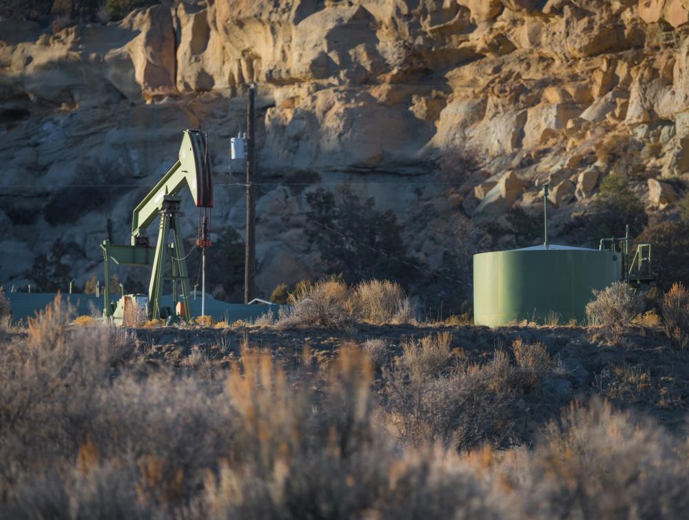 Pump jack and other oil and gas extraction equipment in a rocky desert landscape