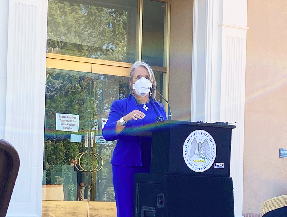 New Mexico Governor Michelle Lujan Grisham stands in front of a podium