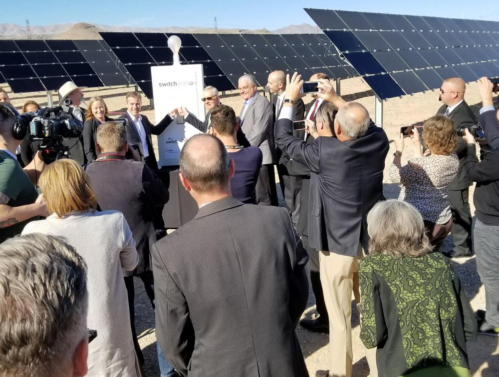 Crowd of people viewed from behind in foreground, former Sen. Harry Reid in background flipping "on" switch at the Dry Lake Solar Energy Zone in Nevada