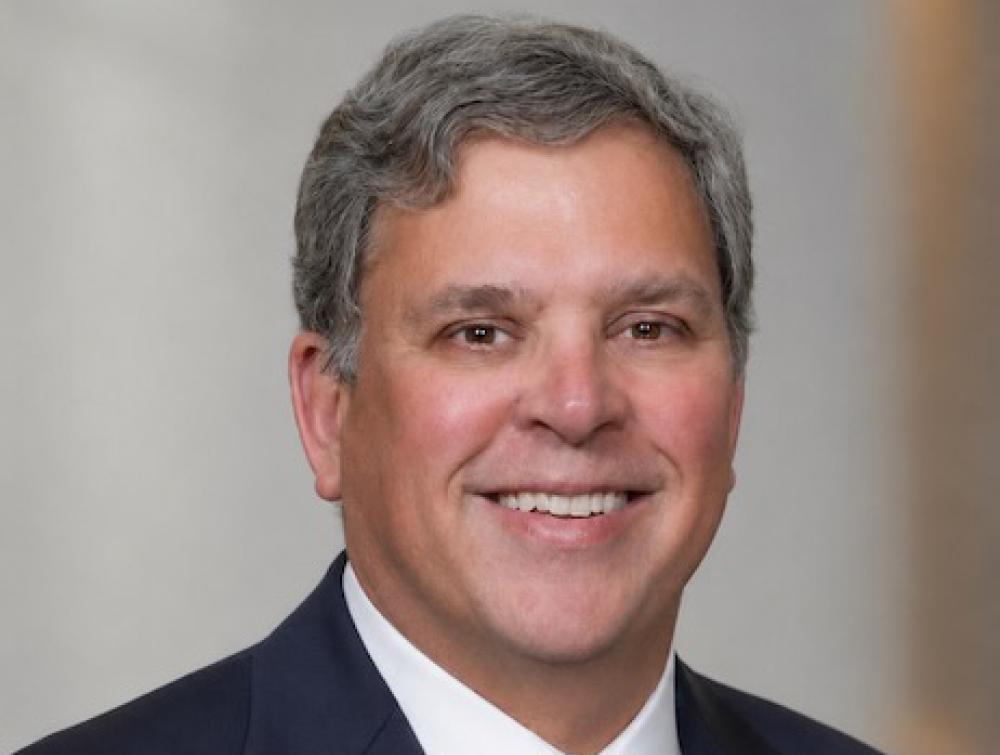 Portrait-style photo of smiling man wearing suit and tie
