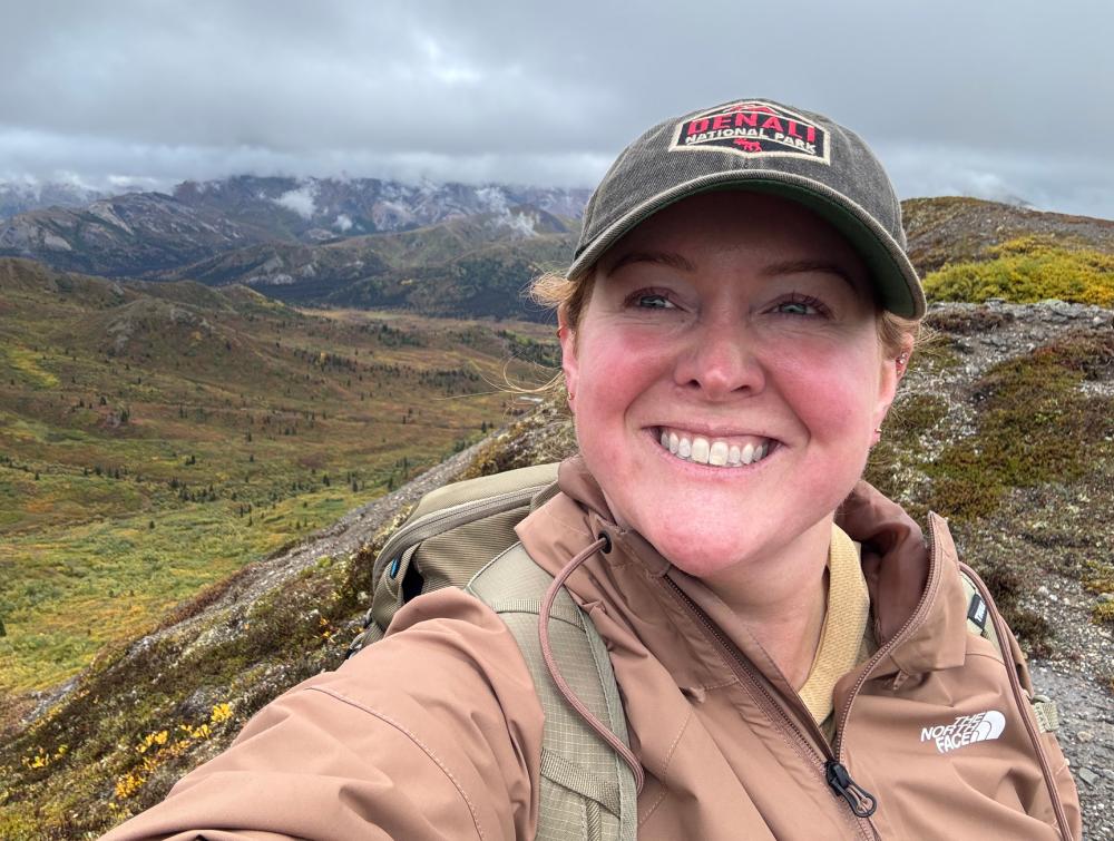 Woman standing outside with mountainous landscape behind her