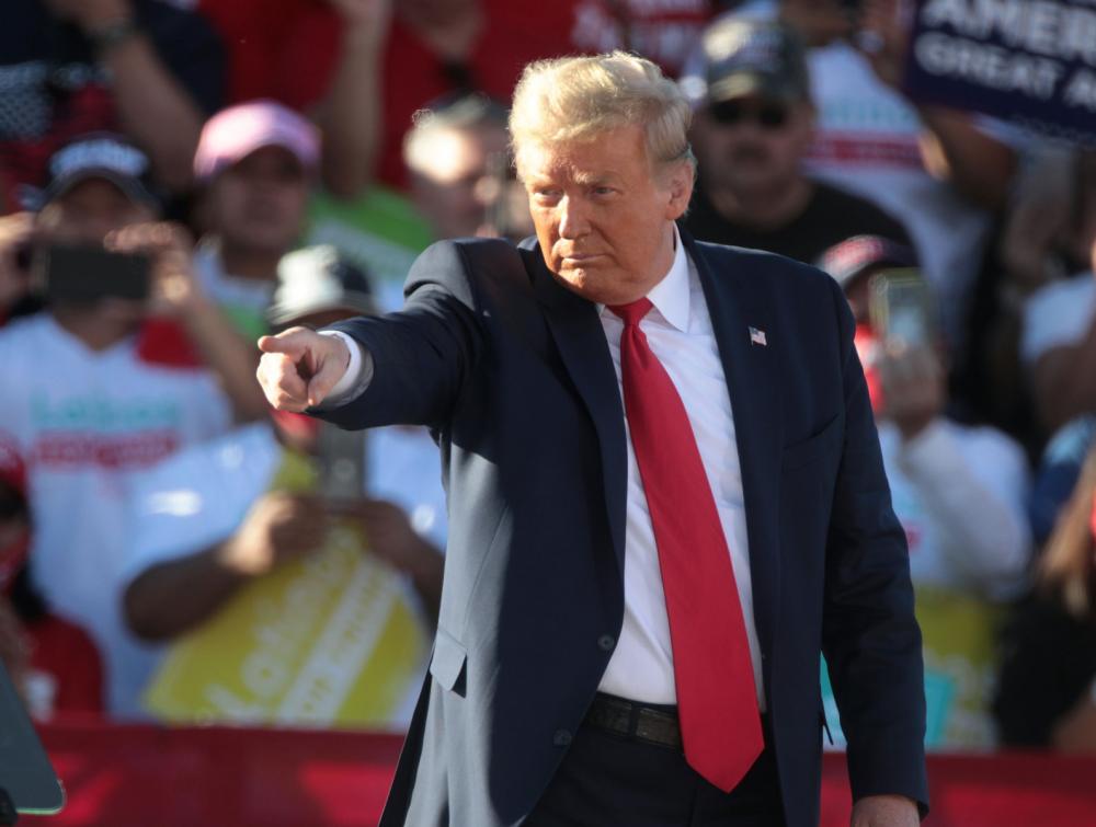 President Trump pointing at something with a crowd of people behind him