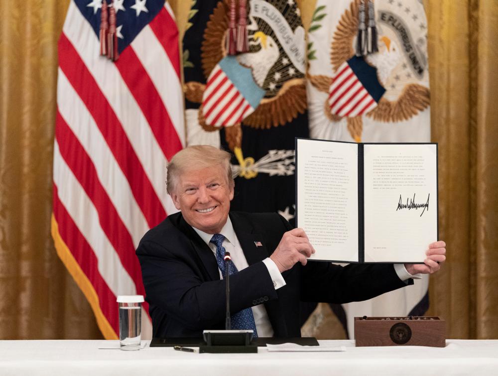 President Trump holding signed proclamation with an American flag over his right shoulder