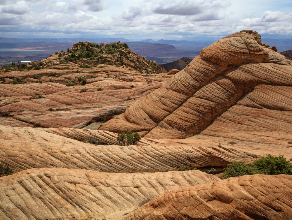 Undulating rocky formations in desert underneath cloudy skies