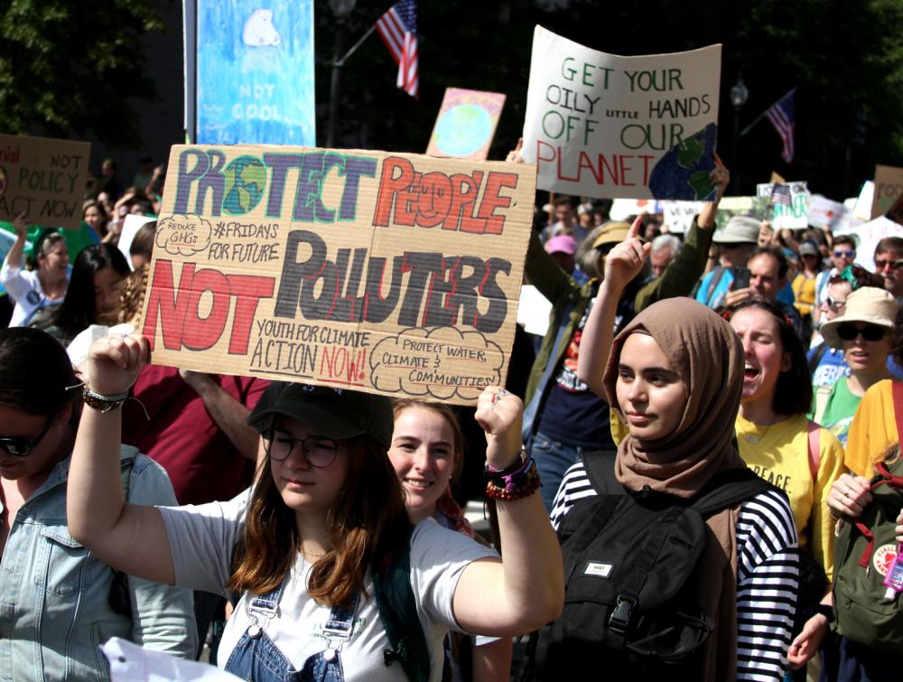 Women in foreground marching at rally and holding signs during Global Climate Strike in 2019 in Washington, DC 