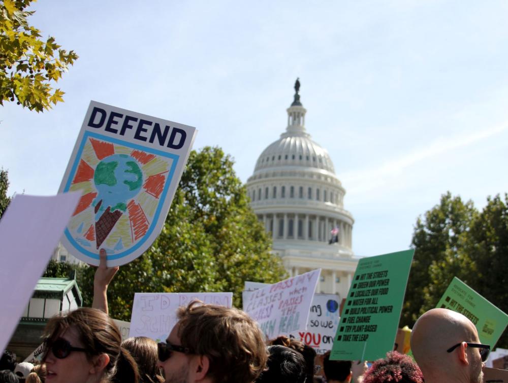Climate signs with U.S. Capitol building in background in Washington, D.C.