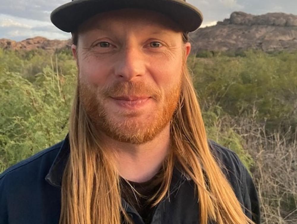 selfie of man with long hair wearing a cap