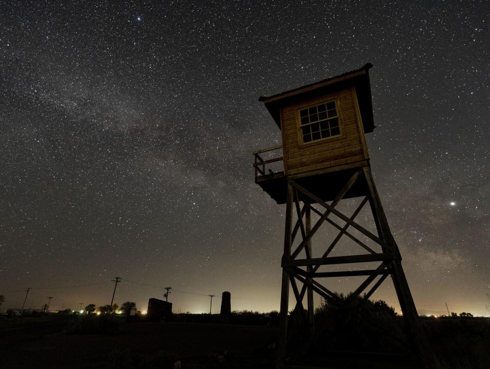 Tall Guard tower at night with stars and city lights behind