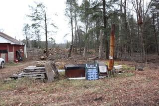 Equipment for maple syrup creation sits with a bunch of trees fallen in the background.