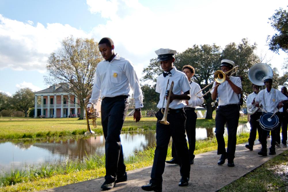 a group of people in a brass band playing instruments as they walk next to a lake