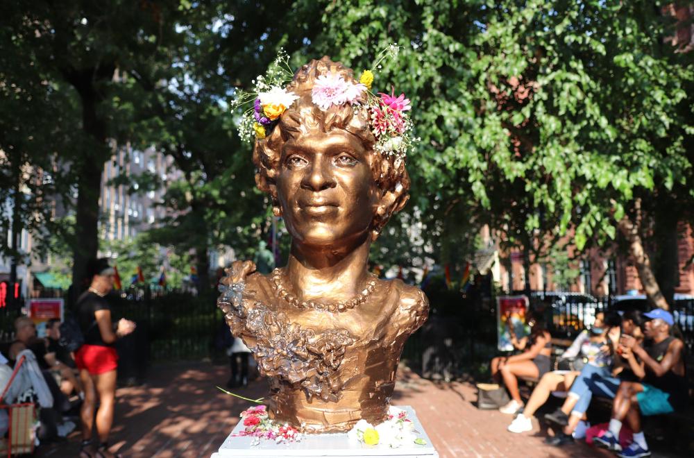 bronze statue of face of Marsha P. Johnson, with real flowers decorating her hair