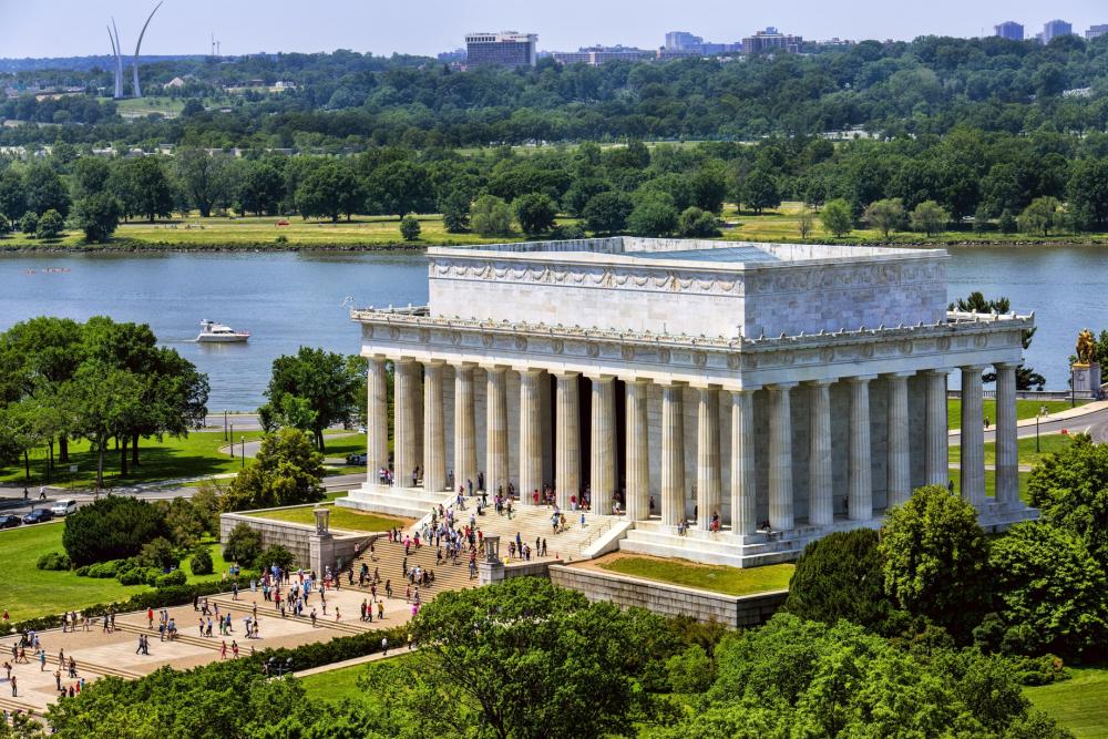 An aerial view of the marble Lincoln Memorial with people walking up and down the stairs and the surrounding areas