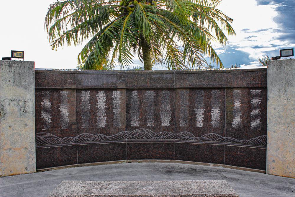 granite panels inscribed with names with a palm tree in the back.