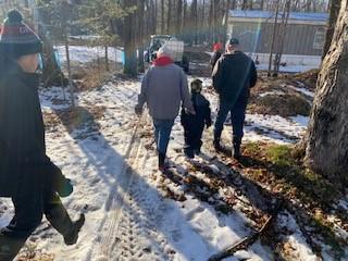 A family walks towards a vehicle in cold weather. Snow is on the ground.