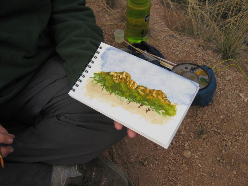 Pad of paper with watercolor painting of mountains, held by man