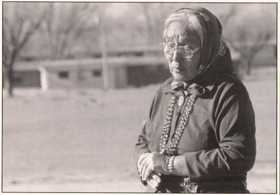 An elderly Navajo woman wearing a scarf and glasses.