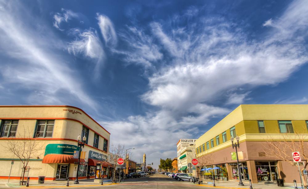 Two yellow two-story buildings in downtown Bakersfield with a blue sky on top.