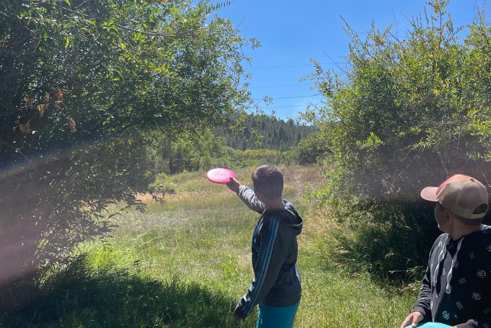 kid throwing disc playing disc golf