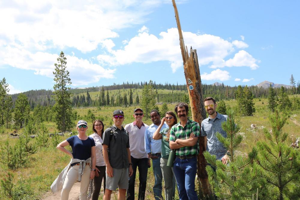 Group of people posing with green rolling hills and trees behind them