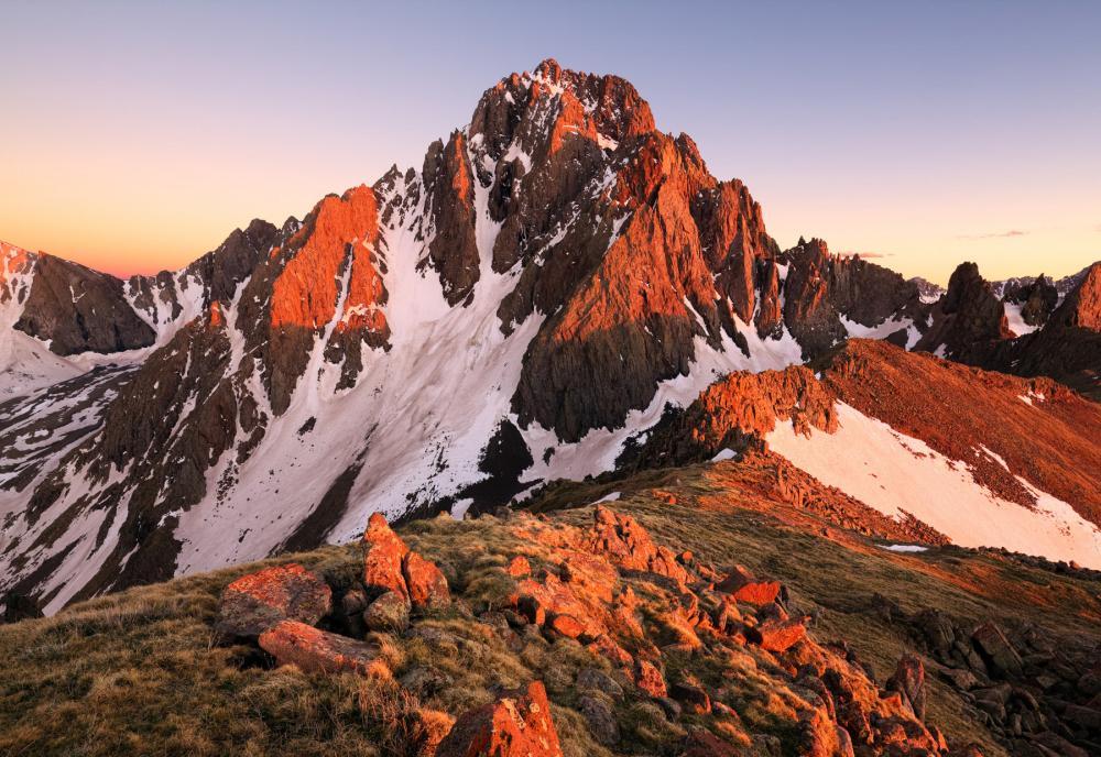 Orange light glowing on mountain dappled with snow in the proposed Whitehouse Addition to Mount Sneffels Wilderness, Colorado