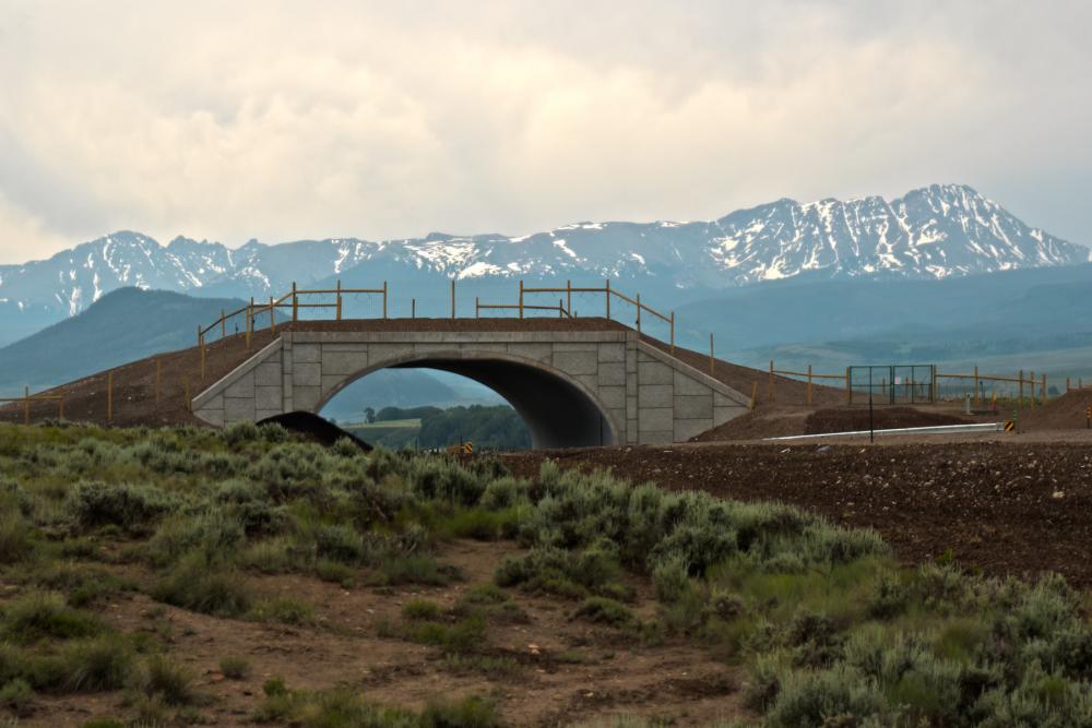 Bridge crossing roadway with mountains in the background